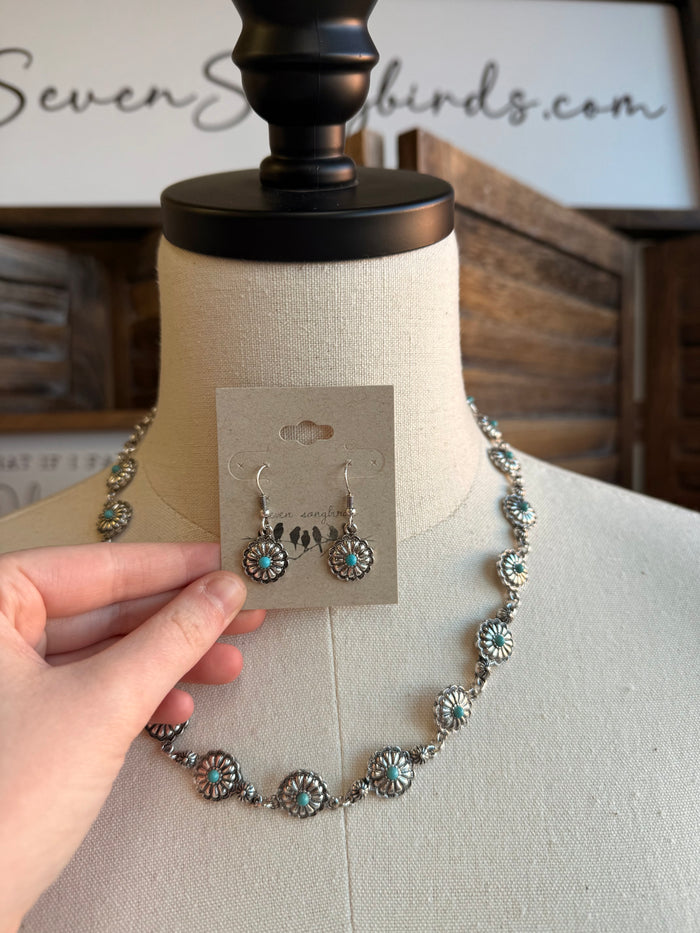 Silver-toned concho drop earrings with turquoise stone accents, on display card