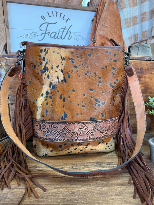 Fringed cowhide crossbody purse with front flap, speckled brown-and-cream hide, tassels