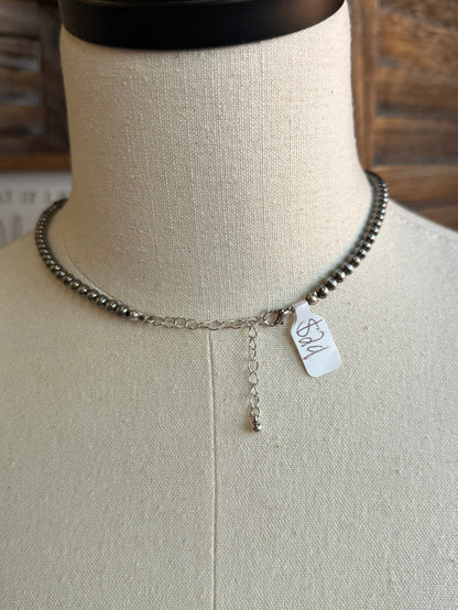Silver-tone beaded necklace with dangling charm and attached tag