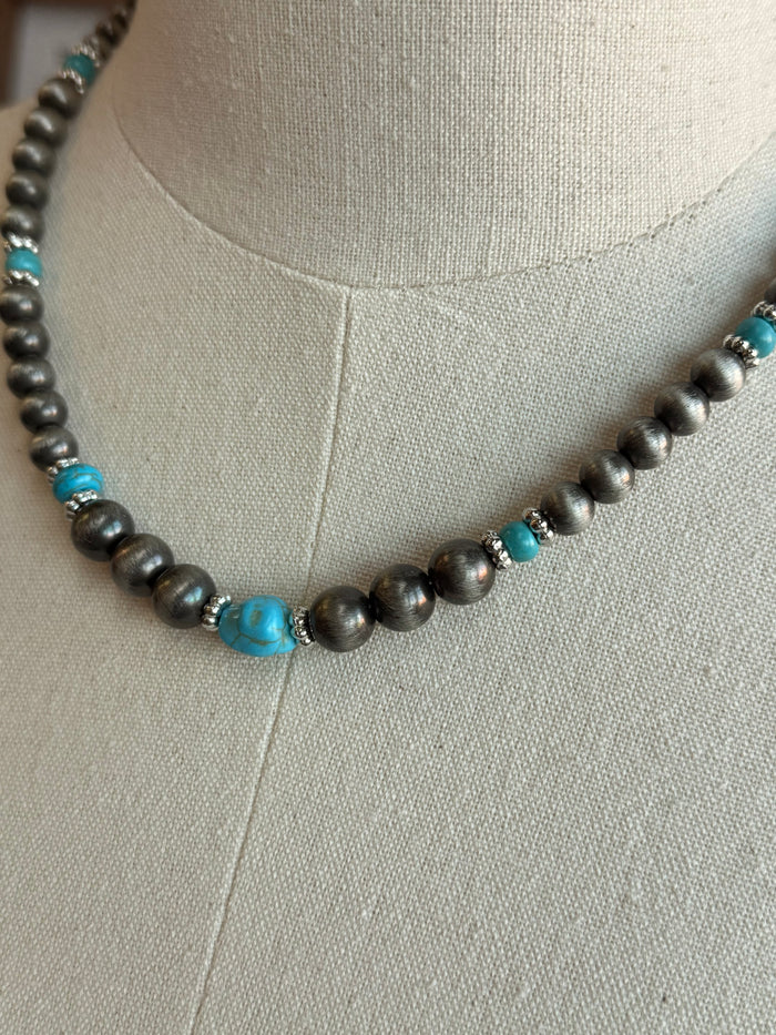 Close-up beaded necklace: silver-toned pearls with turquoise blue bead accents