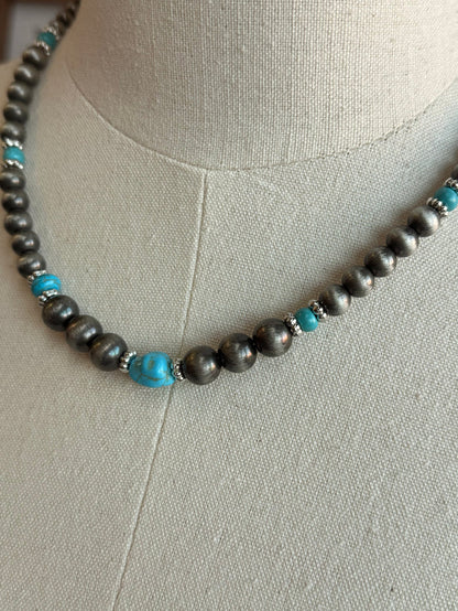 Close-up beaded necklace: silver-toned pearls with turquoise blue bead accents