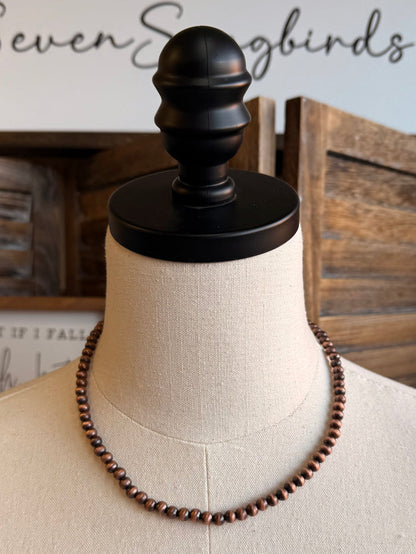 Copper-toned 16-inch pearl bead necklace draped on mannequin bust