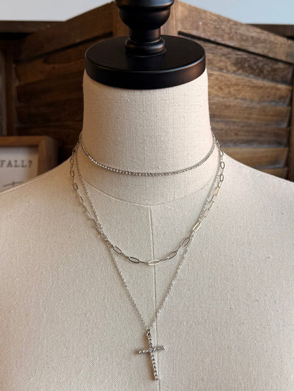 Silver stack necklace with cross pendant and double-chain layers on a mannequin