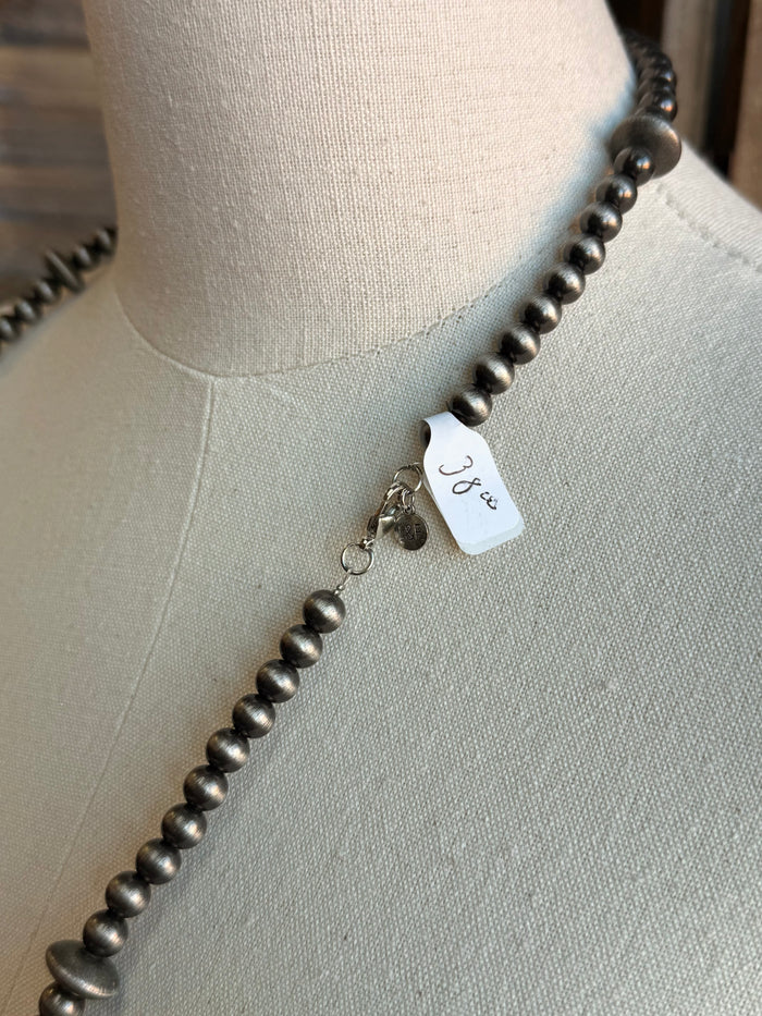 Silver-tone pearl bead necklace with small charm tag on the strand