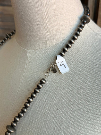 Silver-tone pearl bead necklace with small charm tag on the strand