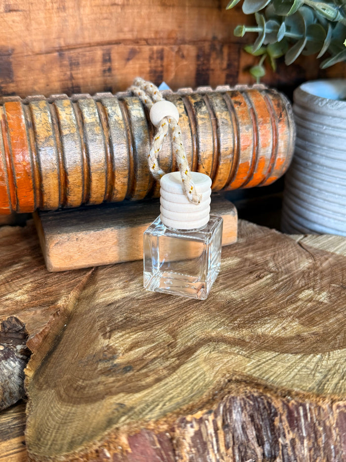 Mini reed diffuser with clear bottle and white stacked reed caps on wooden block