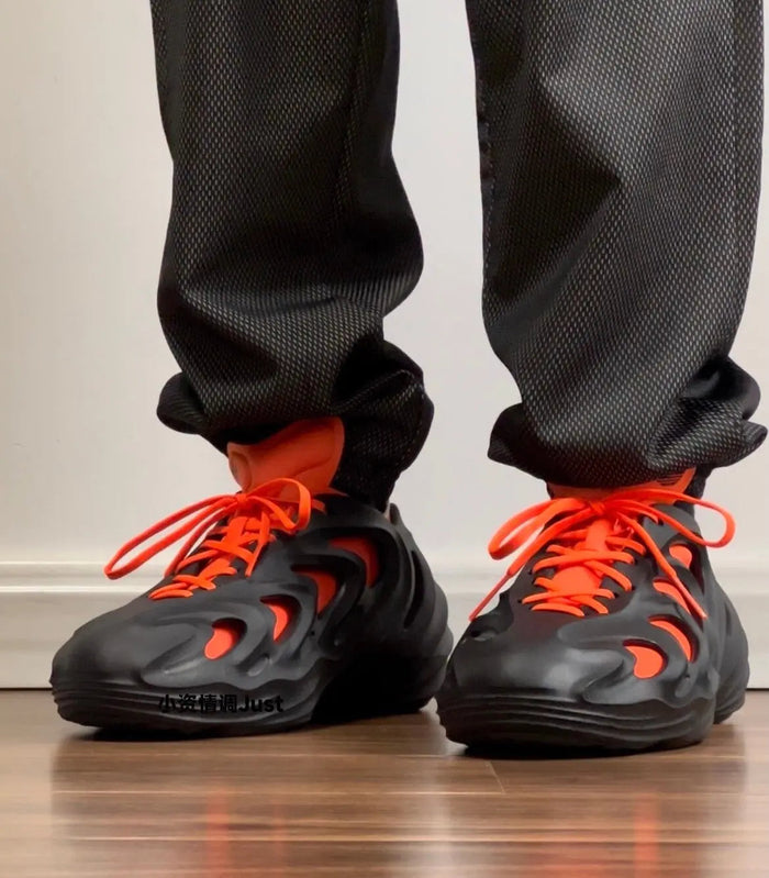 Adidas Adifom Q sneakers: black uppers with orange laces, worn with black socks