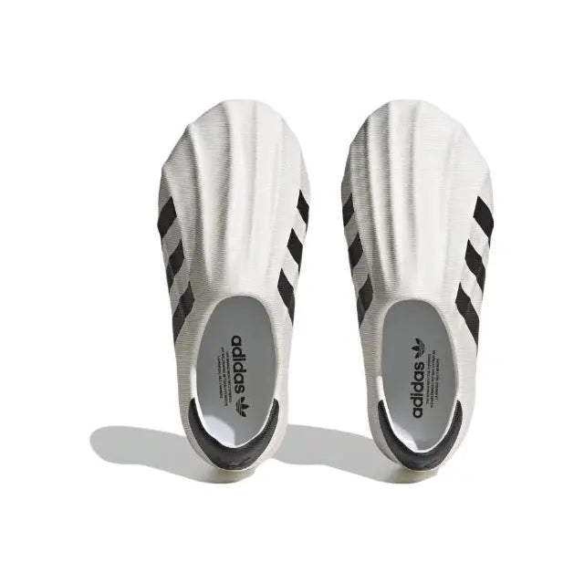 White slip-on sneakers with black stripes and adidas logo on heel