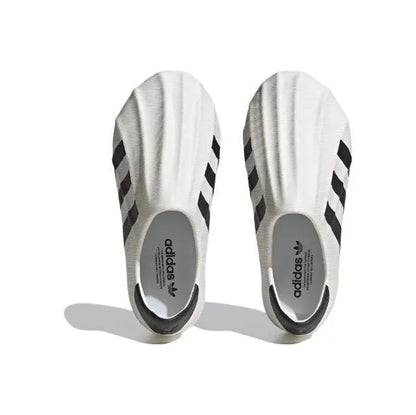 White slip-on sneakers with black stripes and adidas logo on heel