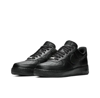 Black low-top sneaker pair, side view with lace-up, toe perforations and swoosh