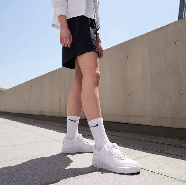Person wearing white Nike Air Force 1 low sneakers and white crew socks