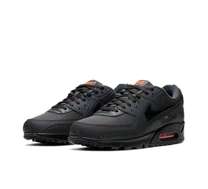 Nike Air Max 90 sneakers, pair view, dark charcoal black with orange heel details and Air unit