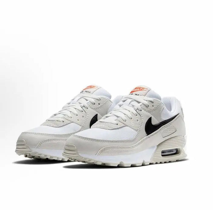 Nike Air Max 90 sneakers, side view in white/beige with black swoosh and orange heel tabs