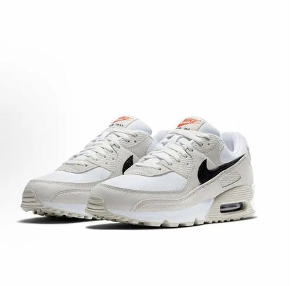 Nike Air Max 90 sneakers, side view in white/beige with black swoosh and orange heel tabs