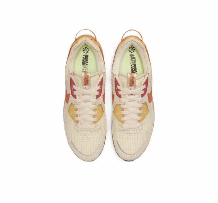 Air Max 90 sneaker pair, cream uppers with orange Swoosh and lace eyelet details