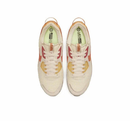 Air Max 90 sneaker pair, cream uppers with orange Swoosh and lace eyelet details