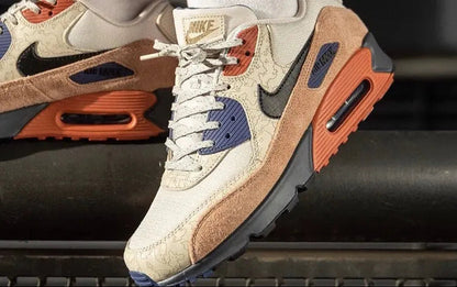 Nike Air Max 90 close-up: cream leather, navy suede, brown panels, orange air unit