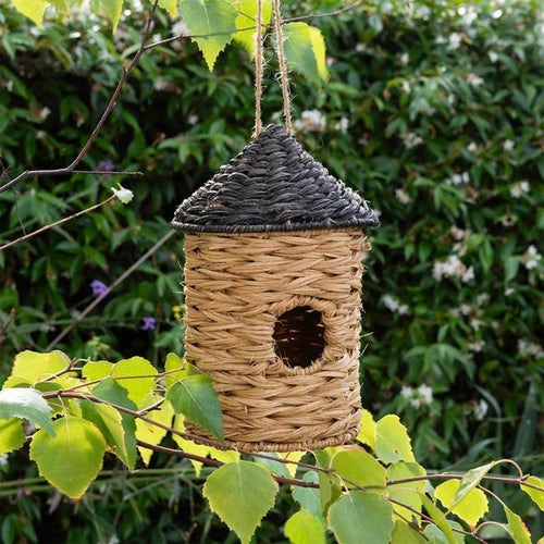 rattan bird house with rounded shape and entrance opening, hanging in garden setting