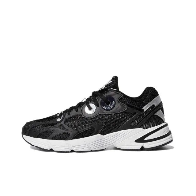 Black low-top Adidas sneakers with white midsole stripes and round eyelet lace panel