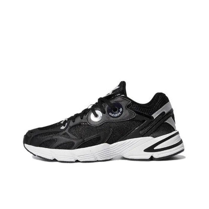 Black low-top Adidas sneakers with white midsole stripes and round eyelet lace panel