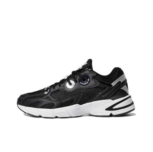 Black low-top Adidas sneakers with white midsole stripes and round eyelet lace panel