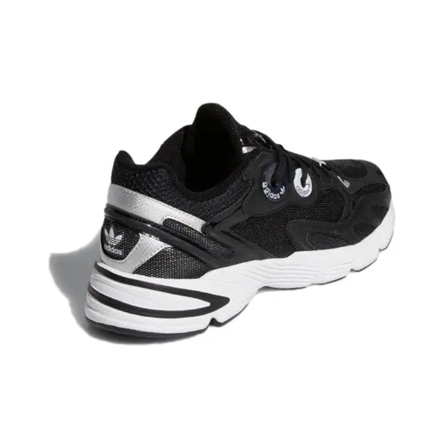 Black low-top sneakers with white heel stripes and textured side panels, chunky sole