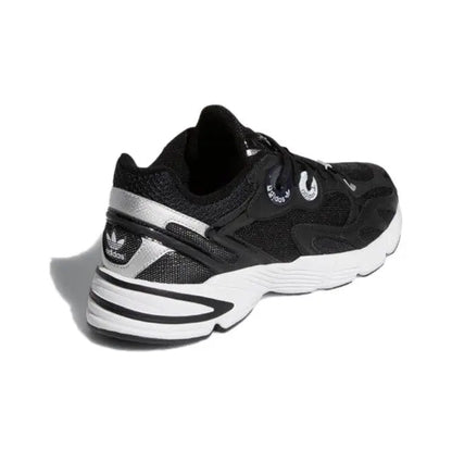 Black low-top sneakers with white heel stripes and textured side panels, chunky sole