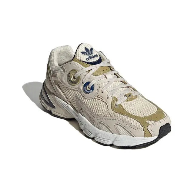 Cream and light-gold lace-up sneaker with mesh texture, padded collar, navy heel tab