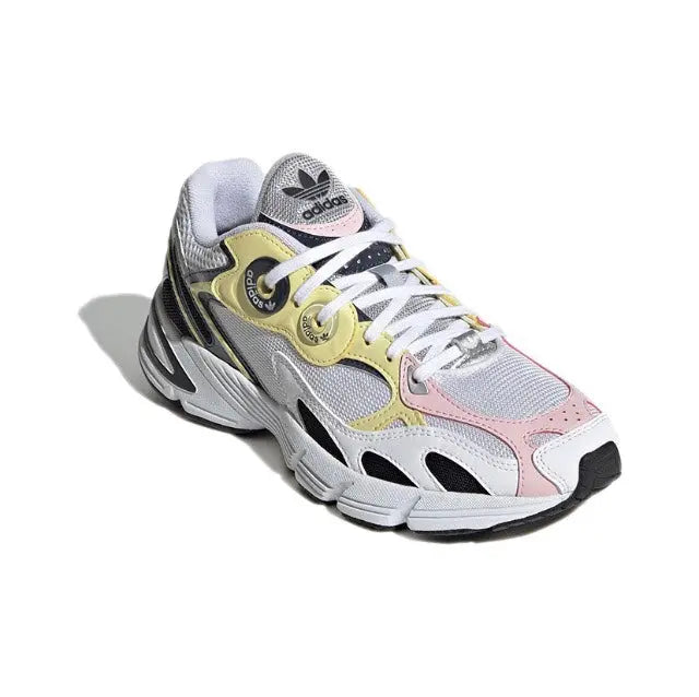 Adidas Astir sneaker, angled front; white mesh with pink accents and yellow logo patch.
