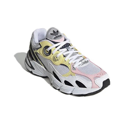 Adidas Astir sneaker, angled front; white mesh with pink accents and yellow logo patch.