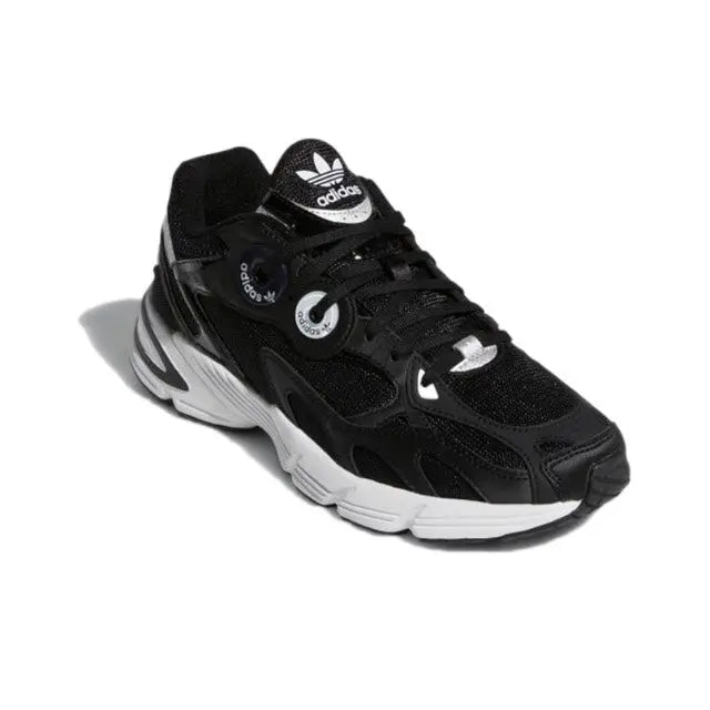 Black low-top Adidas sneakers with white accents, lace-up front, and logo details