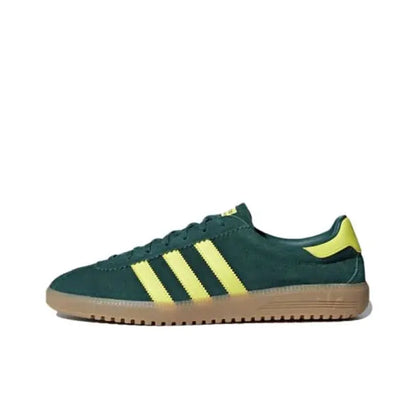 Low-top sneakers in dark green with yellow three-stripe accents and gum sole