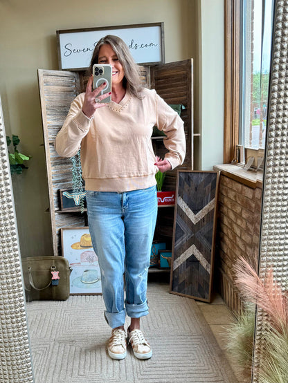 Light beige crewneck sweatshirt with gold studs on neckline and ribbed cuffs