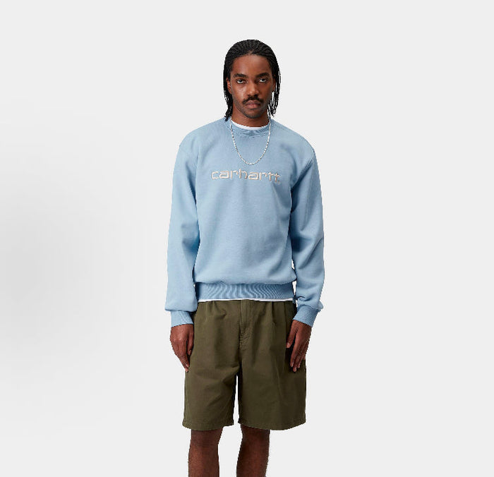 Carhartt WIP crewneck sweatshirt, light blue, worn with long sleeves and chest logo
