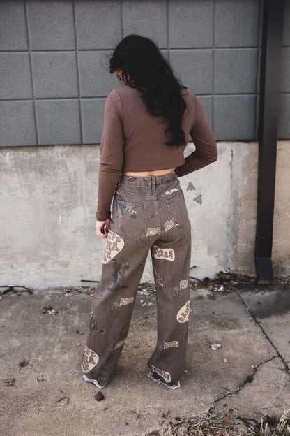 Dark wash wide-leg jeans with distressed cowboy graphic print, side view