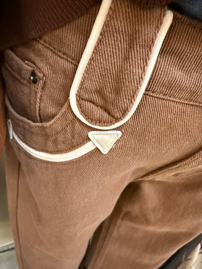 Brown jeans close-up: white-edged pocket with small cream smiley applique
