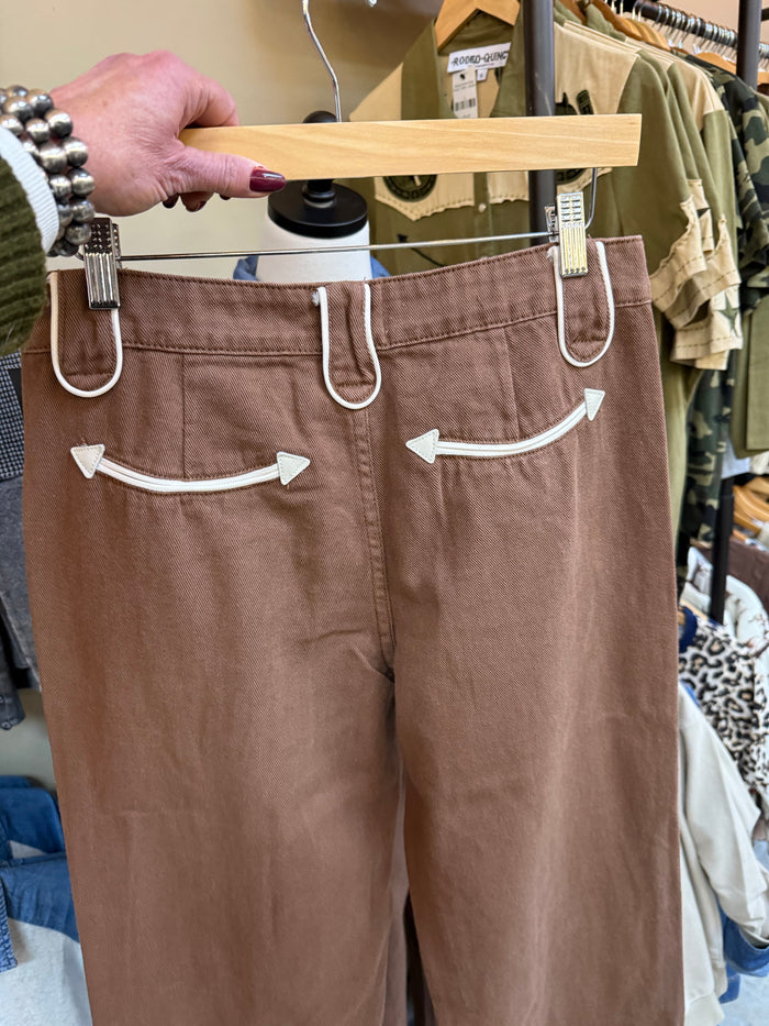 Brown jeans with white-trim front pockets and smiley pocket appliques