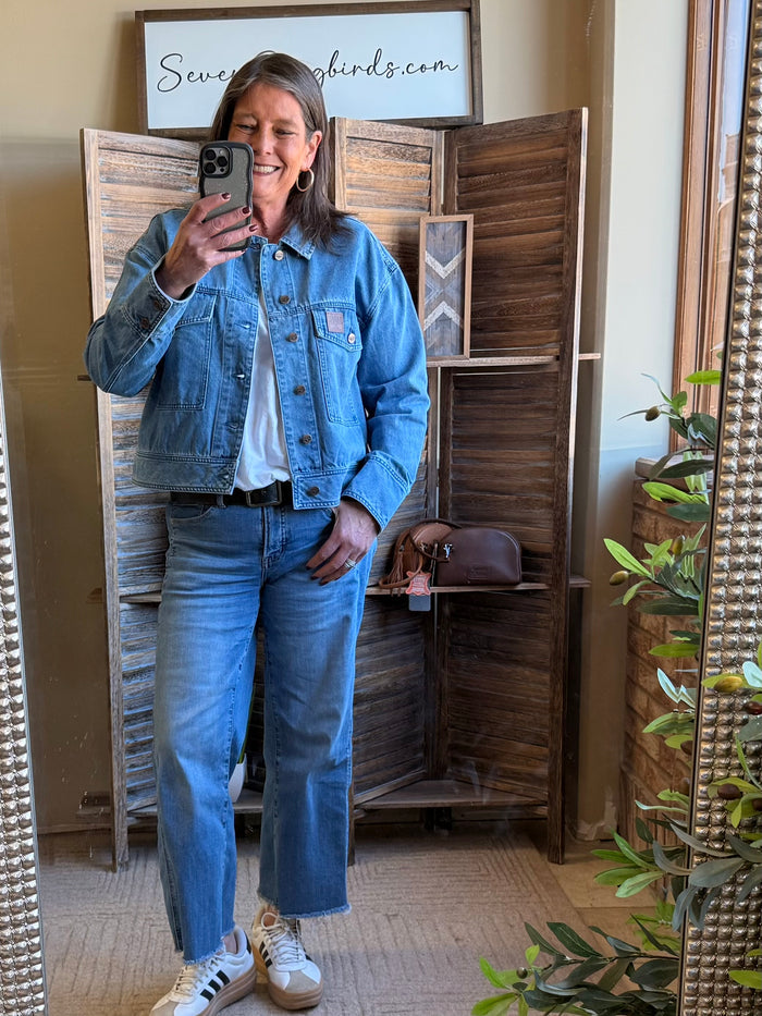 Blue denim jacket with button cuffs and chest pockets in a light wash