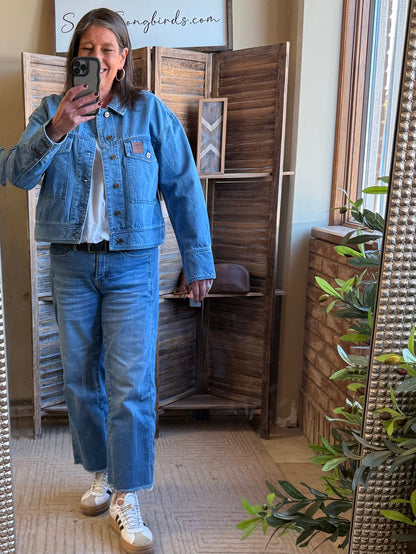 Blue denim jacket with classic collar and chest flap pockets, worn with jeans