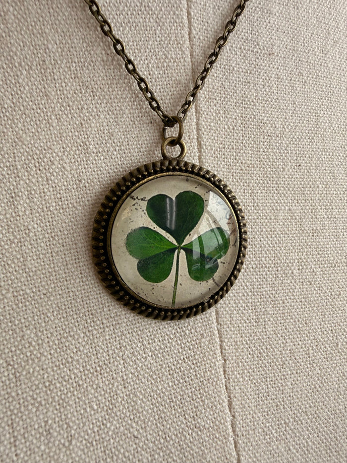 Round clover glass pendant with green four-leaf design on bronze chain