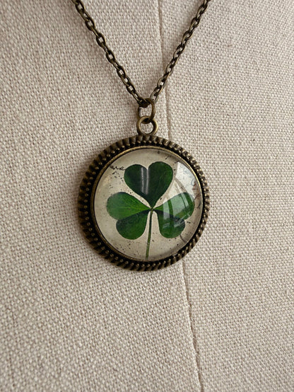 Round clover glass pendant with green four-leaf design on bronze chain