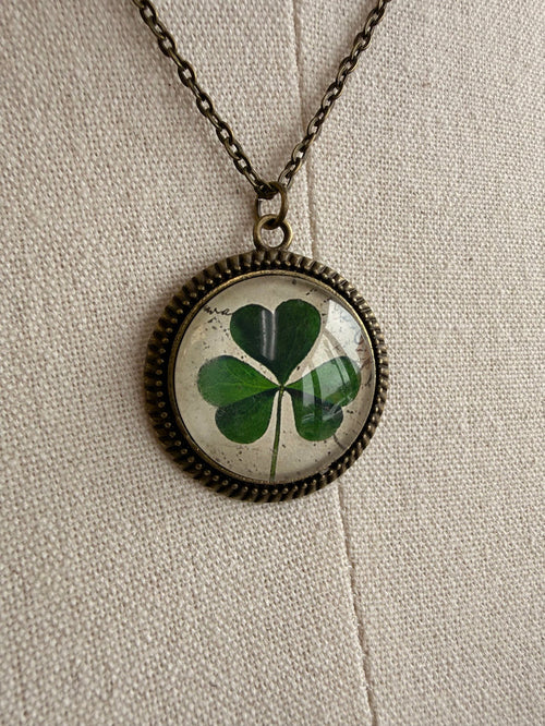 Round clover glass pendant with green four-leaf design on bronze chain