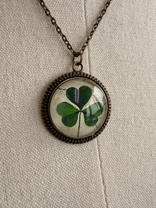 Round clover glass pendant with green four-leaf design on bronze chain