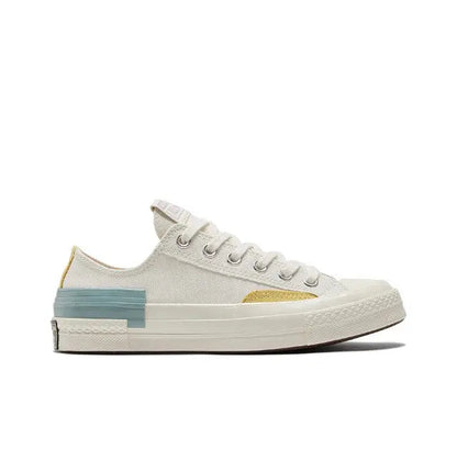 Low-top sneakers side profile, white canvas with yellow chevron and blue heel stripe