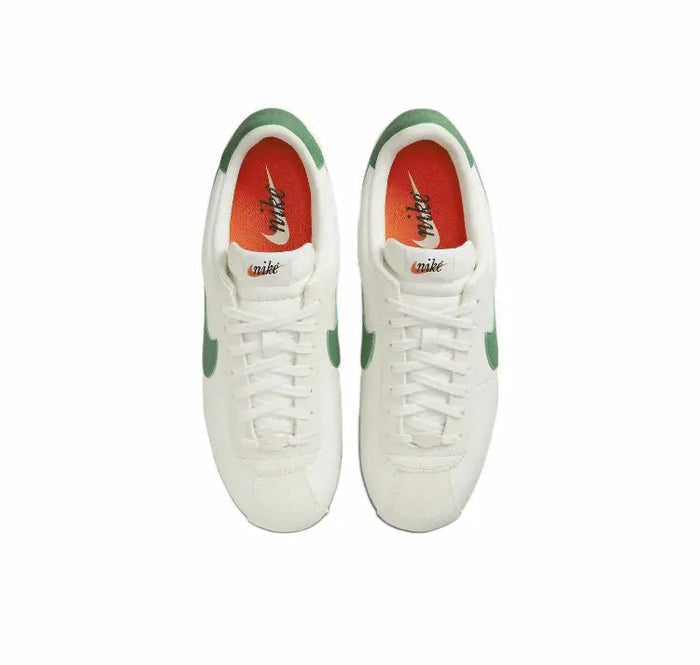Low-top sneakers pair with white laces, red/orange inner lining, green accents