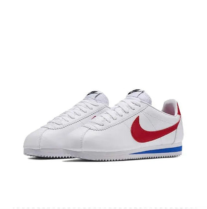 White Nike Cortez sneakers, two-quarter view, red swoosh and blue outsole stripe