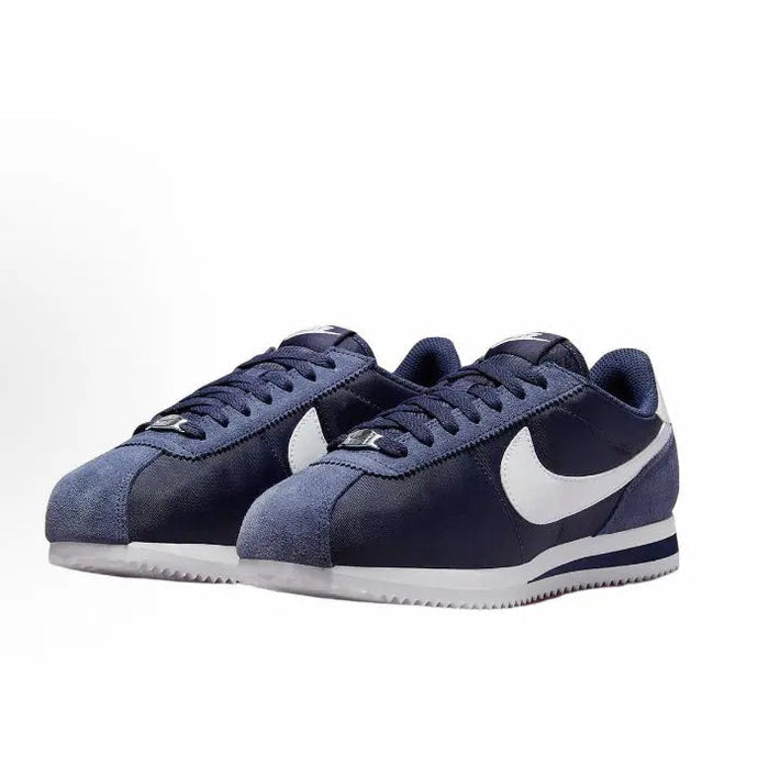 Dark blue low-top sneakers with white swoosh, lace-up front and white sole