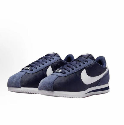 Dark blue low-top sneakers with white swoosh, lace-up front and white sole