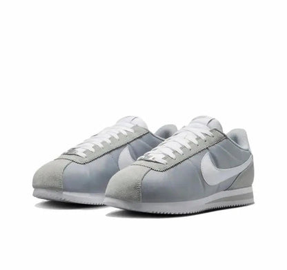 Nike low-top sneakers with white laces, light gray suede, and pale blue panels