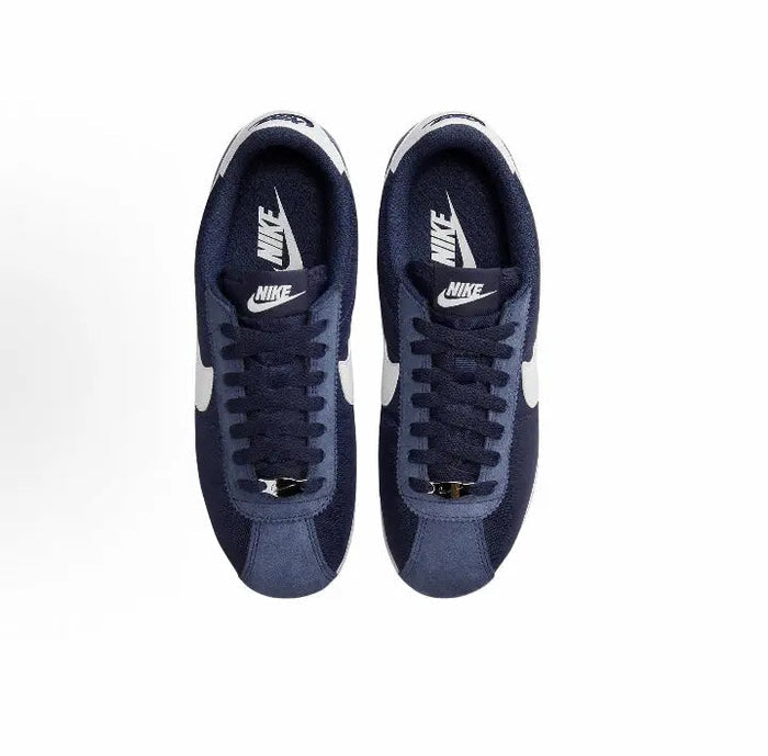 Pair of dark blue Nike sneakers with white heel tabs and navy lace-up uppers